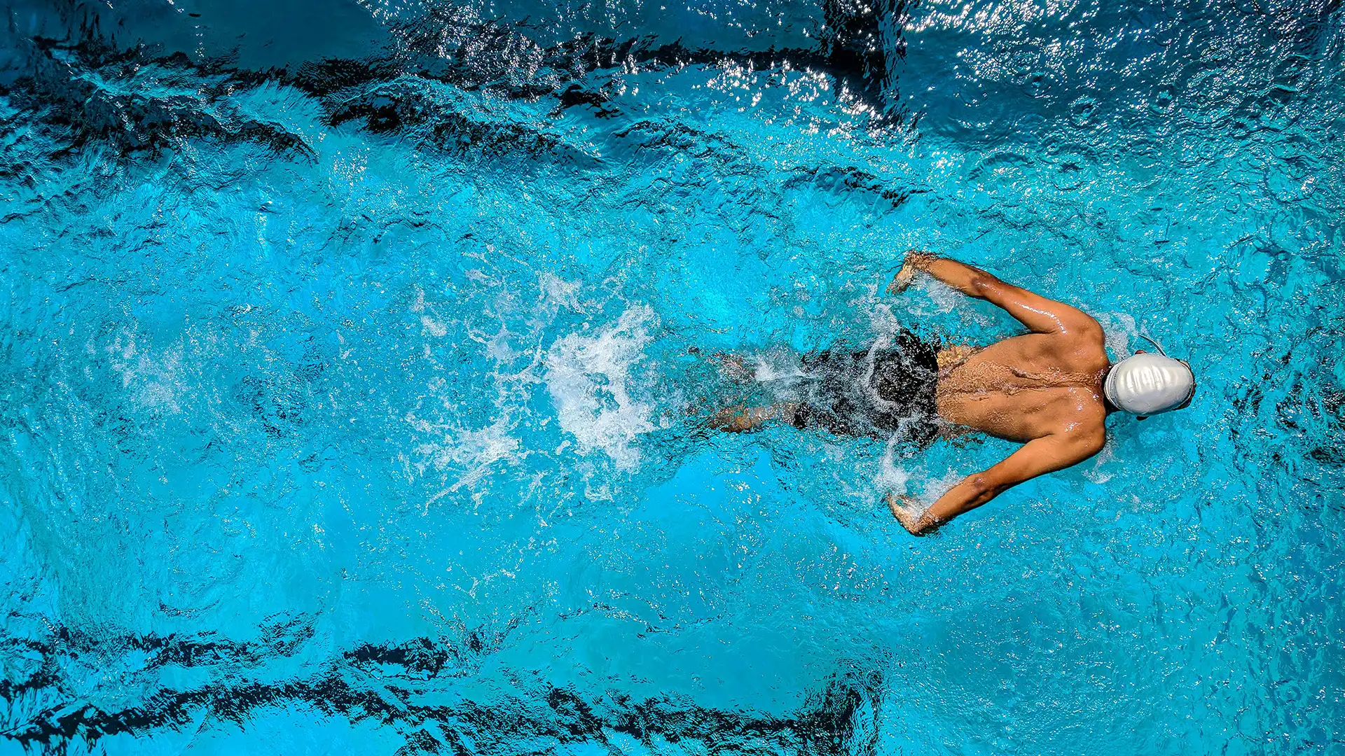 Swimmer completing laps in an indoor pool, showcasing facilities that balance athletic performance with sustainability in sport.
